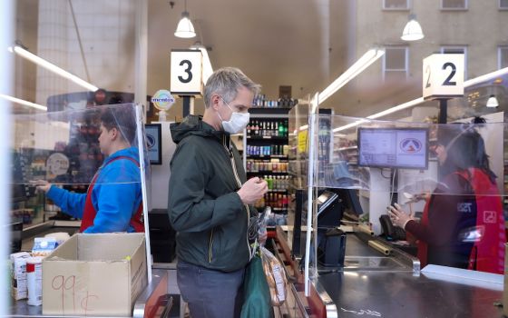 Grocery store check out March 28, 2020, shows pandemic precautions, masks and partitions. (CNS/Reuters/Caitlin Ochs)