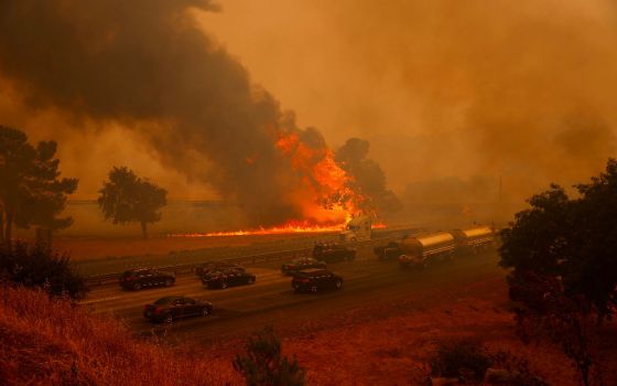 Motorists on Interstate 80 drive past flames drive past flames from the LNU lighting complex fire near Vacaville, CA, on Aug. 19, 2020. (CNS photo/Stephen Lam, Reuters)