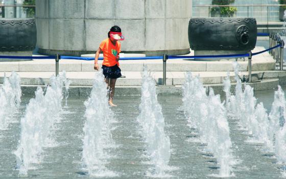 Child playing in a fountain with a sprinkler 