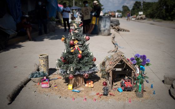 A Christmas tree and a nativity scene on the roadside, alongside provisional shelters that stretch for miles, outside San Pedro Sula, Honduras. (© Sean Hawkey)