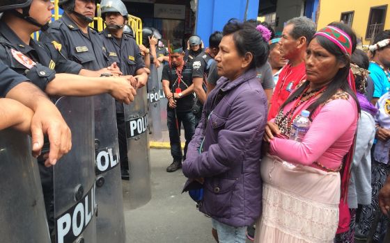 Indigenous women protesting oil pollution in the Peruvian Amazon face off with police outside the Congress building in Lima in 2016. (Barbara Fraser)