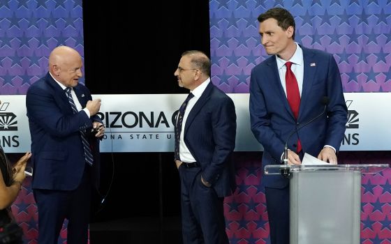 Arizona Republican Senate candidate Blake Masters, right, looks on as Democratic Sen. Mark Kelly, left, talks with Libertarian candidate Marc Victor ahead of a televised debate in Phoenix Oct. 6. 