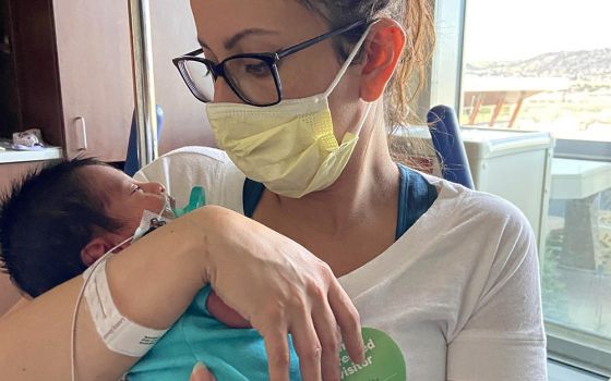 Estefanía Madrigal sits in a wheelchair propped up after her surgery, holding baby Oliver in the neonatal intensive care unit in April 2020 in Lonetree, Colorado. (Courtesy of Estefanía Madrigal)