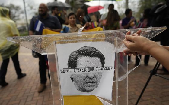 An image of Florida Gov. Ron DeSantis is overlaid with the words "Don't attack our democracy" at a rally to denounce the governor's immigration policies Sept. 20 in Doral, Florida. (AP/Rebecca Blackwell)