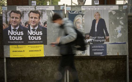 A man walks in front of campaign posters of French President Emmanuel Macron and far-right presidential candidate Marine Le Pen in Sevres, outside Paris, France, April 20. (AP/Christophe Ena)