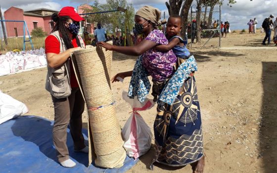 Joseanair Hermes, program manager for Catholic Relief Services in the Cabo Delgado province, at left, distributes relief aid to families displaced by armed conflict in the district of Metuge in the province. (Courtesy of Catholic Relief Services/Caritas/A
