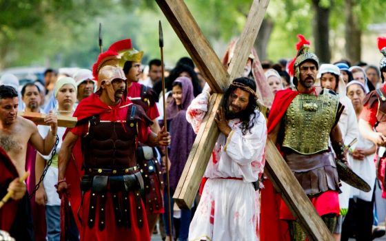 A man portraying Jesus carries a cross down a neighborhood street during a live re-enactment of the Stations of the Cross outside All Saints Catholic Church in Houston on Good Friday, April 14, 2017. (CNS/Catholic Herald/James Ramos)