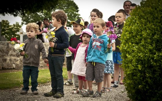 Schoolchildren in Graignes, France, wait to place flowers on a memorial during a ceremony on June 5, 2015, honoring those who died during the Battle of Graignes in 1944. (Wikimedia Commons/U.S. Army/Capt. Saska Ball)