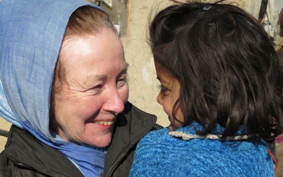 Kathy Kelly holds a child at the Chamin-E-Babrak refugee camp in Kabul, Afghanistan, in January 2014, a few days after the child had been saved from a burning tent, during a fire that destroyed much of the camp. (Abdulhai Darya)