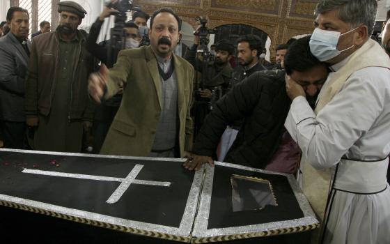 A clergyman comforts a relative of Christian priest Father William Siraj, 75, who was killed by gunmen, during his funeral service at the All-Saints Church, in Peshawar, Pakistan, Jan. 31, 2022. (AP Photo/Muhammad Sajjad)