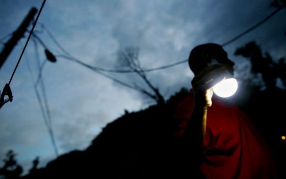 A man uses a solar lamp while walking in the dark May 11 in Jayuya, Puerto Rico, where the fragile power system was still reeling from the devastation caused by Hurricane Maria eight months before. (CNS/Reuters/Alvin Baez)