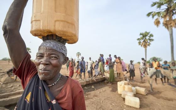 A woman carries water from a well in Lugi, a village in the Nuba Mountains of Sudan. (CNS photo/Paul Jeffrey)