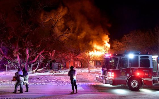 Residents in Abilene, Texas, walk past their burning house Feb. 15. Firefighters were only able to draw water from one hydrant because because cold-weather power outages affected water treatment plants. (CNS photo/Ronald W. Erdrich, Reporter-News, USA Tod