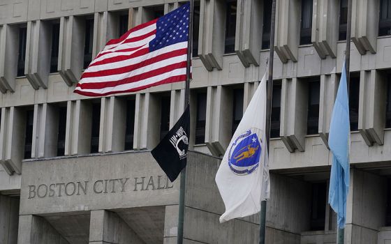 The American flag, the Commonwealth of Massachusetts flag, and the City of Boston flag, from left, fly outside Boston City Hall May 2. (AP/Charles Krupa)