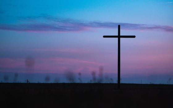 Cross seen in field during sunrise or sunset (Unsplash/Aaron Burden)