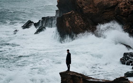 Man standing on rocky shore of Algeria (Unsplash/Benoumechiara)