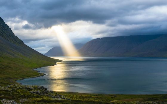 Sunbeam coming down from clouds into a body of water (Unsplash/Davide Cantelli)
