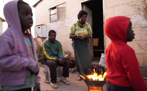 Jeffrey Carlos, center, sits outside his house with his family Aug. 3 on the outskirts of Harare, Zimbabwe. (AP photo/Tsvangirayi Mukwazhi)