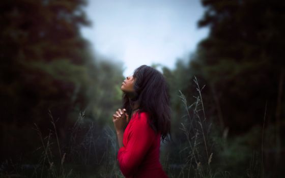 A person prays at a nature preserve in Auckland, New Zealand. (Unsplash/Diana Simumpande)