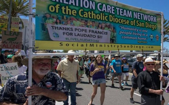 Fr. Emmet Farrell, right, carries a banner for the Diocese of San Diego's creation care team network during a climate march in March 2017. (Provided photo)