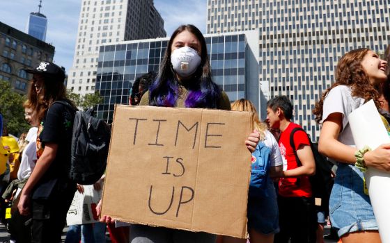 A young woman wears an air-filtering mask and holds a sign while participating in the Global Climate Strike in New York City in September 2019. (CNS photo/Gregory A. Shemitz) 