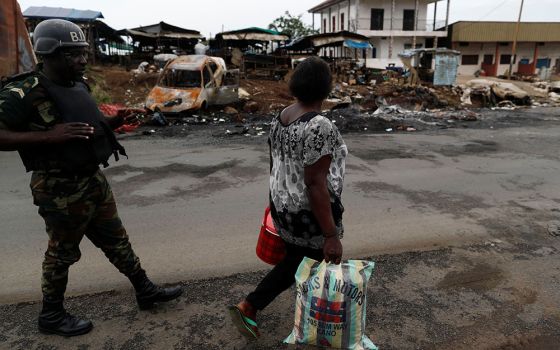 A woman walks past a soldier of the Cameroon army's elite Rapid Intervention Battalion in the city of Buea in the Anglophone Southwest Region Oct. 4, 2018. (Newscom/Reuters/Zohra Bensemra)