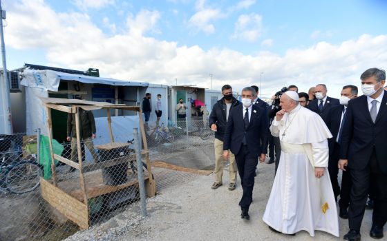 Refugees stand outside their shelters as Pope Francis visits the government-run Reception and Identification Center Dec. 5 in Mytilene, Greece. (CNS/Vatican Media)