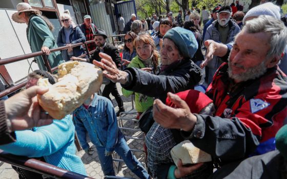 People receive bread during the May 8 distribution of humanitarian aid in the southern port city of Mariupol, Ukraine, during the Russian invasion. (CNS/Reuters/Alexander Ermochenko)