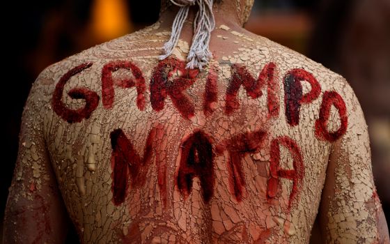 An Indigenous man with a phrase in Portuguese painted on his back that translates to "Mining Kills," participates in a protest against the increase of mining activities that are encroaching on his land. (AP/File/Eraldo Peres)