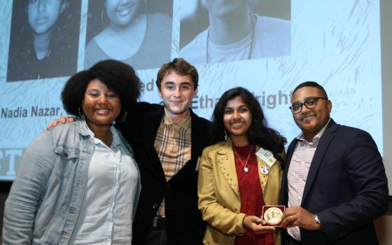 From left, Elsa Mengistu, Ethan Wright and Nadia Nazar from Zero Hour with event emcee Erica Smiley, after the group received its Letelier-Moffitt Human Rights Award (Institute for Policy Studies/Rick Reinhard)