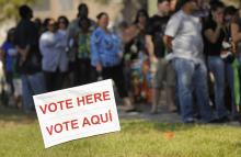 A sign in English and Spanish is seen as people wait to vote in 2012 outside a polling place in Kissimmee, Florida. (CNS/Reuters/Scott A. Miller)