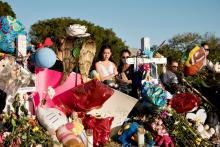 A young woman mourns in front of a memorial to mass shooting victims Feb. 25 at Marjory Stoneman Douglas High School in Parkland, Florida. (CNS/Reuters/Angel Valentin)