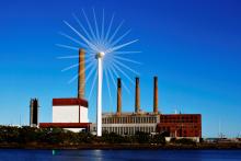 A wind turbine turns in front of a fossil fuel power plant in Charlestown, Mass., in 2013. (CNS/Reuters/Brian Snyder)