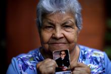 Human rights activist Guadalupe Mejia poses for a picture with a stamp showing Blessed Óscar Romero Oct. 12 at her home in San Salvador, El Salvador. (CNS/Reuters/Jose Cabezas)