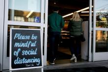 Shoppers enter a Seattle grocery store March 17 near a sign requesting social distancing, following reports of coronavirus cases in the area. (CNS/Reuters/David Ryder)