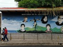 Salvadorans walk past a mural of Salvadoran martyrs Aug. 15, 2020, outside Our Lady of Pilar Catholic Church in Zaragoza, El Salvador. The mural includes St. Óscar Romero and four U.S. churchwomen slain in El Salvador in 1980. (CNS)