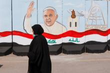A woman walks past a mural of Pope Francis on a wall surrounding a church in Baghdad Feb. 22. (CNS/Reuters/Khalid al-Mousily)