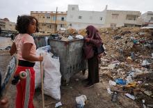 A Tunisian woman and girl look for plastic in a garbage container to earn money in Tunis July 31, 2021. (CNS/Reuters/Ammar Awad)