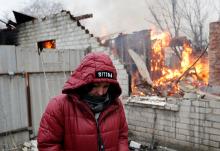 A local resident stands next to her house that caught fire after recent shelling in the separatist-controlled city of Donetsk, Ukraine, Feb. 28. (CNS/Reuters/Alexander Ermochenko)