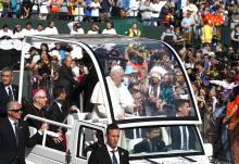 Pope Francis arrives to celebrate Mass at Commonwealth Stadium July 26 in Edmonton, Alberta, Canada. Looking on in the background with headdress is Phil Fontaine, former national chief of the Assembly of First Nations. (CNS/Paul Haring)