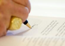 Pope Benedict XVI signs a copy of his encyclical Caritas in Veritate ("Charity in Truth") at the Vatican July 6, 2009. (CNS/L'Osservatore Romano via Reuters)