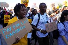 Vanessa Nakate of Uganda, left, participates in a Fridays for Future protest at the COP27 U.N. Climate Summit while holding a sign that says "pay for loss and damage."