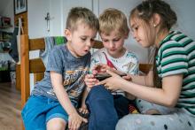 Stanislav Tereshchenko, 5, Janek Sulkowski, 8, and Anastasia Tereshchenko, 9, play Minecraft on a portable tablet at the home of Olga and Mariusz Sulkowski in Otwock, Poland, May 21, 2022. (CNS photo/Lisa Johnston)