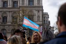 A trans pride flag is seen at an April 2022 trans rights protest in London. The trans flag, which dates to 1999, features light blue and light pink to symbolize the traditional colors for baby girls and baby boys, according to Outright International. The white stripe represents people who identify as intersex, gender neutral or transitioning. (Unsplash/Karollyne Videira Hubert)