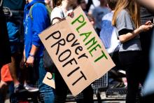 Person at a rally holds a sign that reads: "planet over profit"