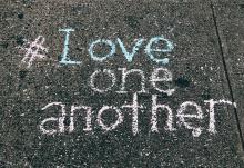 A concrete floor displays the words "#Love one another" written in chalk (Unsplash/Jon Tyson)