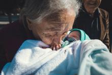 Grandmother kisses a baby on the hand (Unsplash/Tamara Govedarovic)