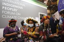 Members of the International Indigenous People's Forum on Climate Change look at their phones Nov. 3 at the COP26 U.N. Climate Summit, in Glasgow, Scotland. (AP photo/Alberto Pezzali)
