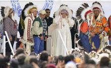 Pope Francis dons a headdress during a visit with Indigenous peoples at Maskwaci, the former Ermineskin Residential School, Monday, July 25, 2022, in Maskwacis, Alberta. (AP Photo/Eric Gay)
