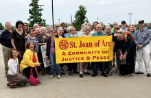 Displaying a banner for St. Joan of Arc Parish, members of St. Joan of Arc/WAMM Peacemakers hold a monthly prayer vigil. (Provided photo)